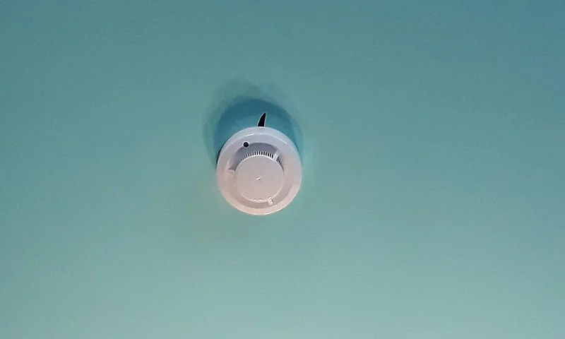 Ceiling-mounted fire and smoke alarm device on a white ceiling
