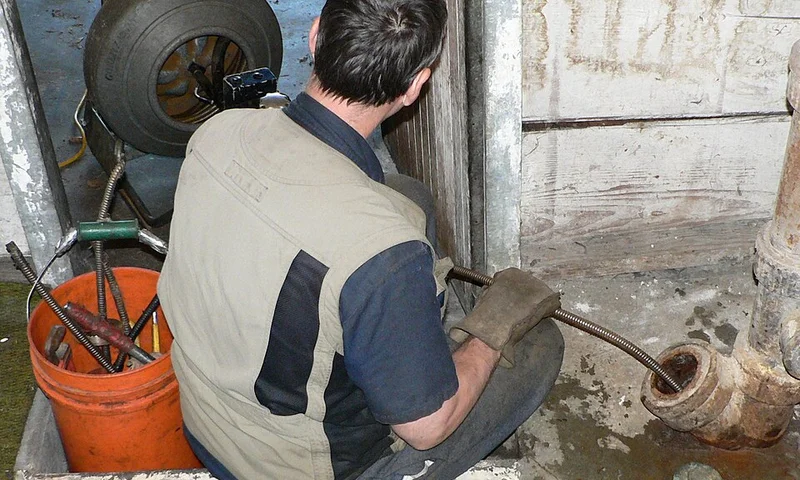 Plumber using a drain snake under a sink