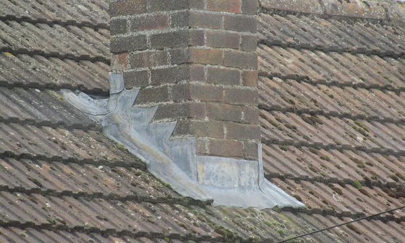 Roofer working on a residential roof near flashing